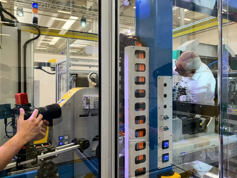 produzione video corporate in azienda, operatore con videocamera riprende una linea di assemblaggio automatica